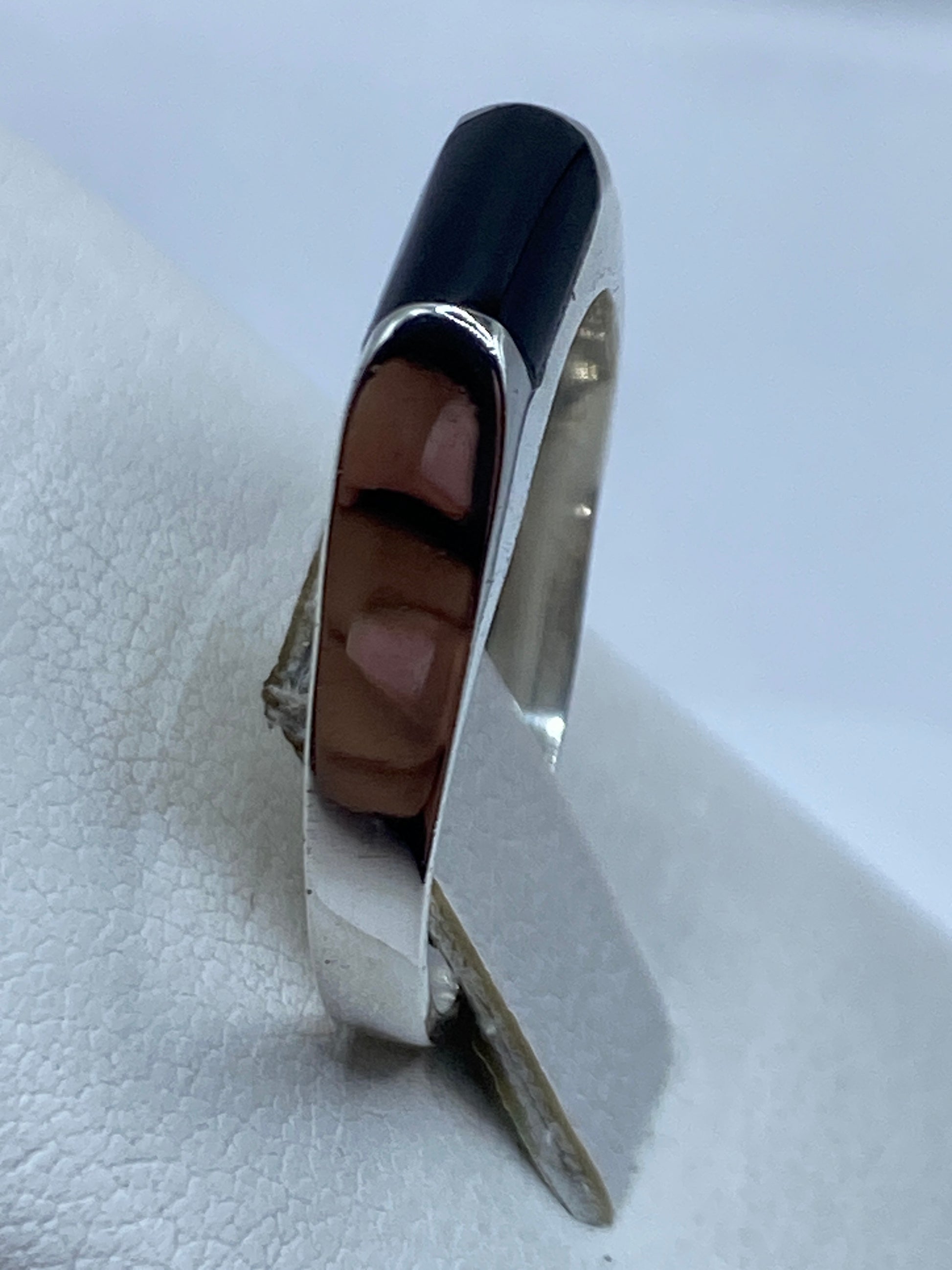 Anillo de plata con ónix negro puesto en la mano, look unisex y versátil