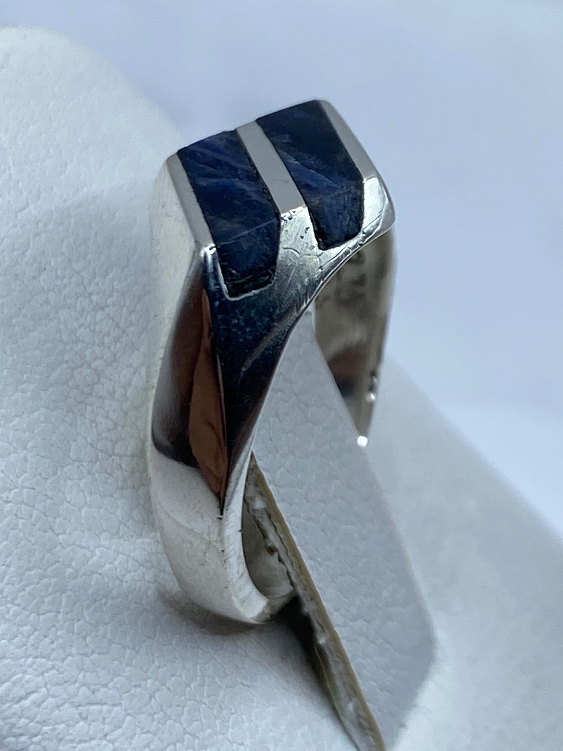 Anillo puesto en dedo mostrando el brillo natural del lapislázuli con vetas doradas