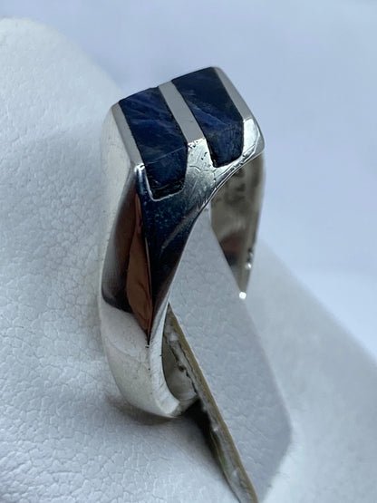 Anillo puesto en dedo mostrando el brillo natural del lapislázuli con vetas doradas