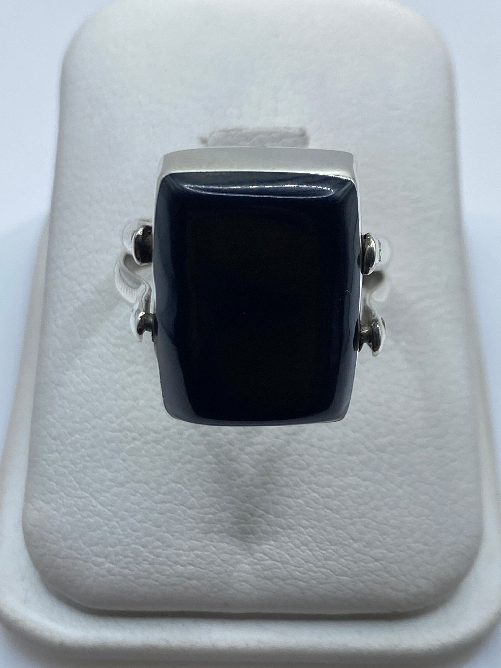 Anillo de plata con ónix negro rectangular en la mano de una mujer adulta