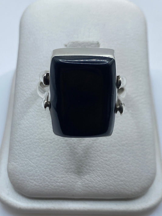 Anillo de plata con ónix negro rectangular en la mano de una mujer adulta