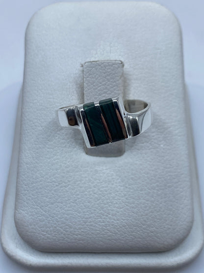 Anillo de plata con malaquita verde natural en la mano de una mujer