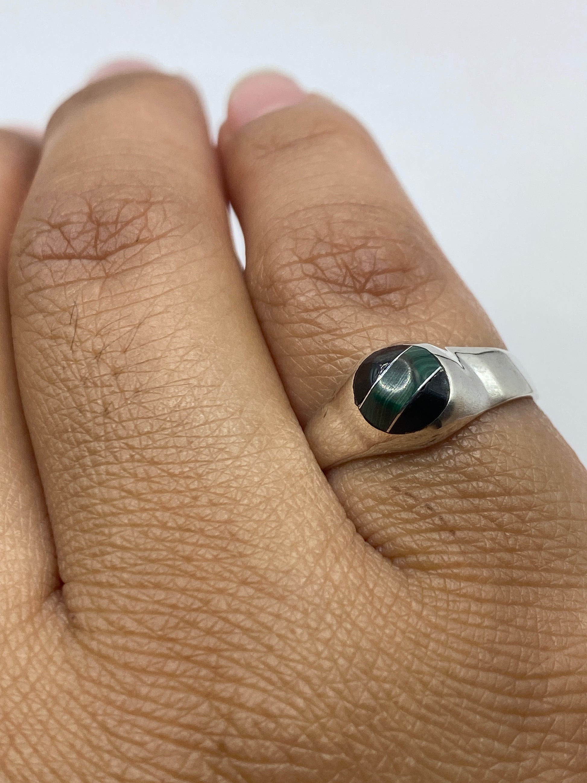Anillo de plata en dedo mostrando la malaquita verde con luz natural