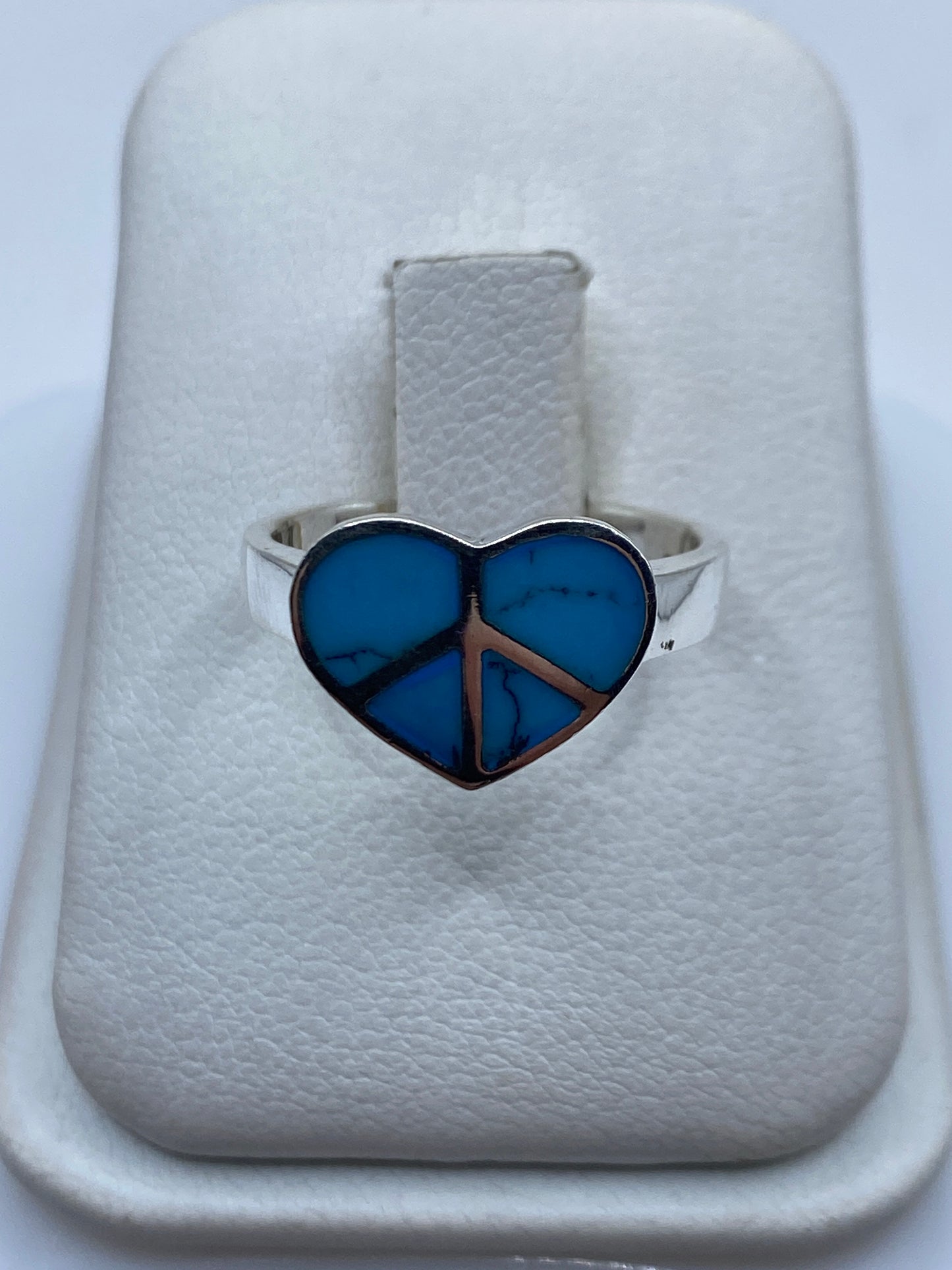 Anillo de plata con turquesa azul cielo y símbolo de paz en la mano de una mujer