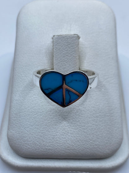 Anillo de plata con turquesa azul cielo y símbolo de paz en la mano de una mujer