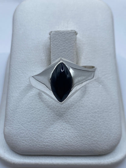 Anillo de plata solitario con ónix negro pulido sobre la mano de una persona