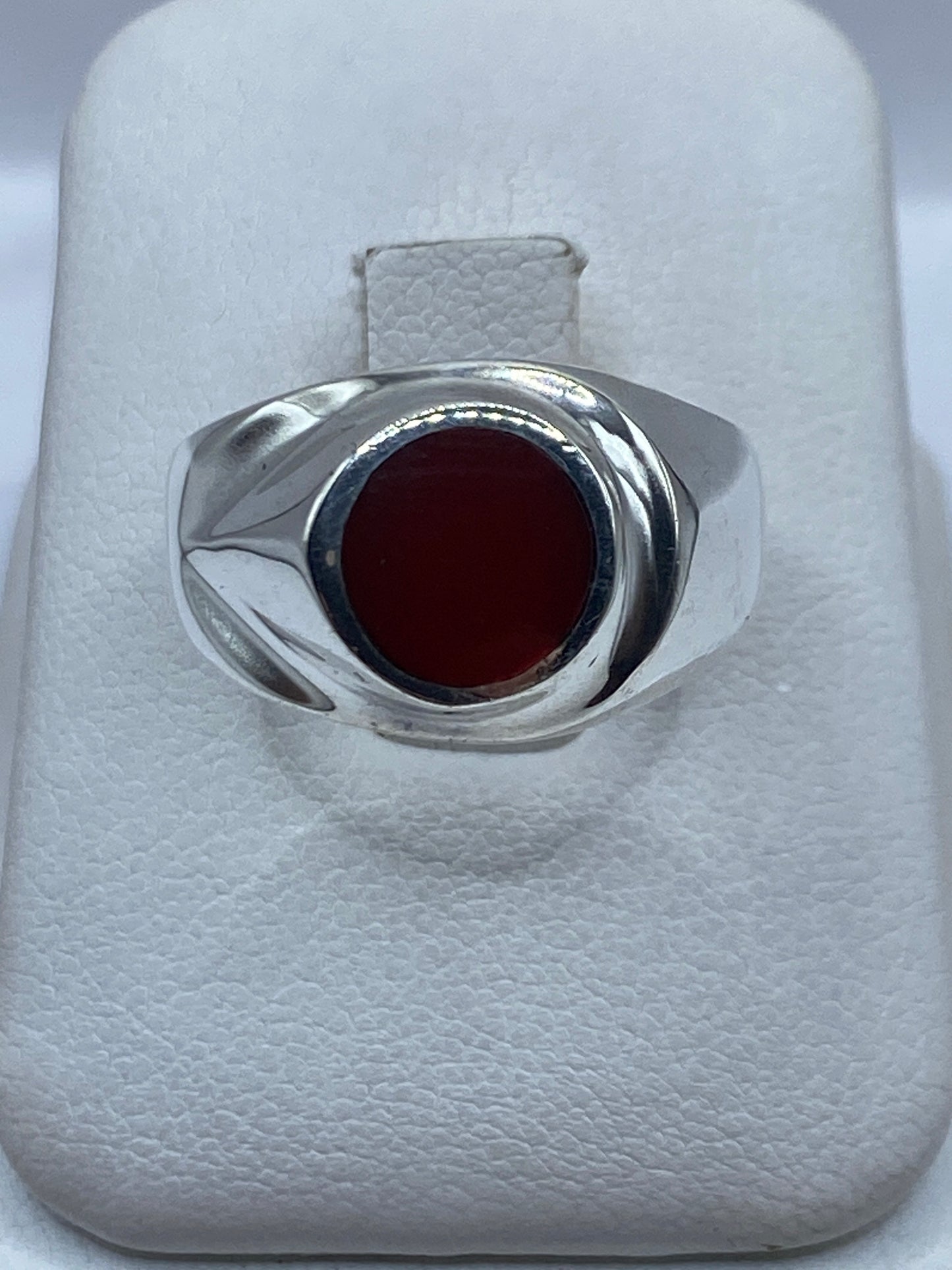 Anillo de plata solitario con coral rojo en la mano de un hombre, vista frontal