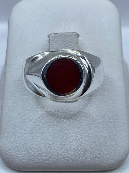 Anillo de plata solitario con coral rojo en la mano de un hombre, vista frontal