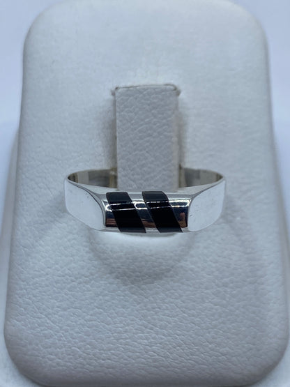 Anillo de plata con ónix negro en banda recta, visto desde frente sobre dedo