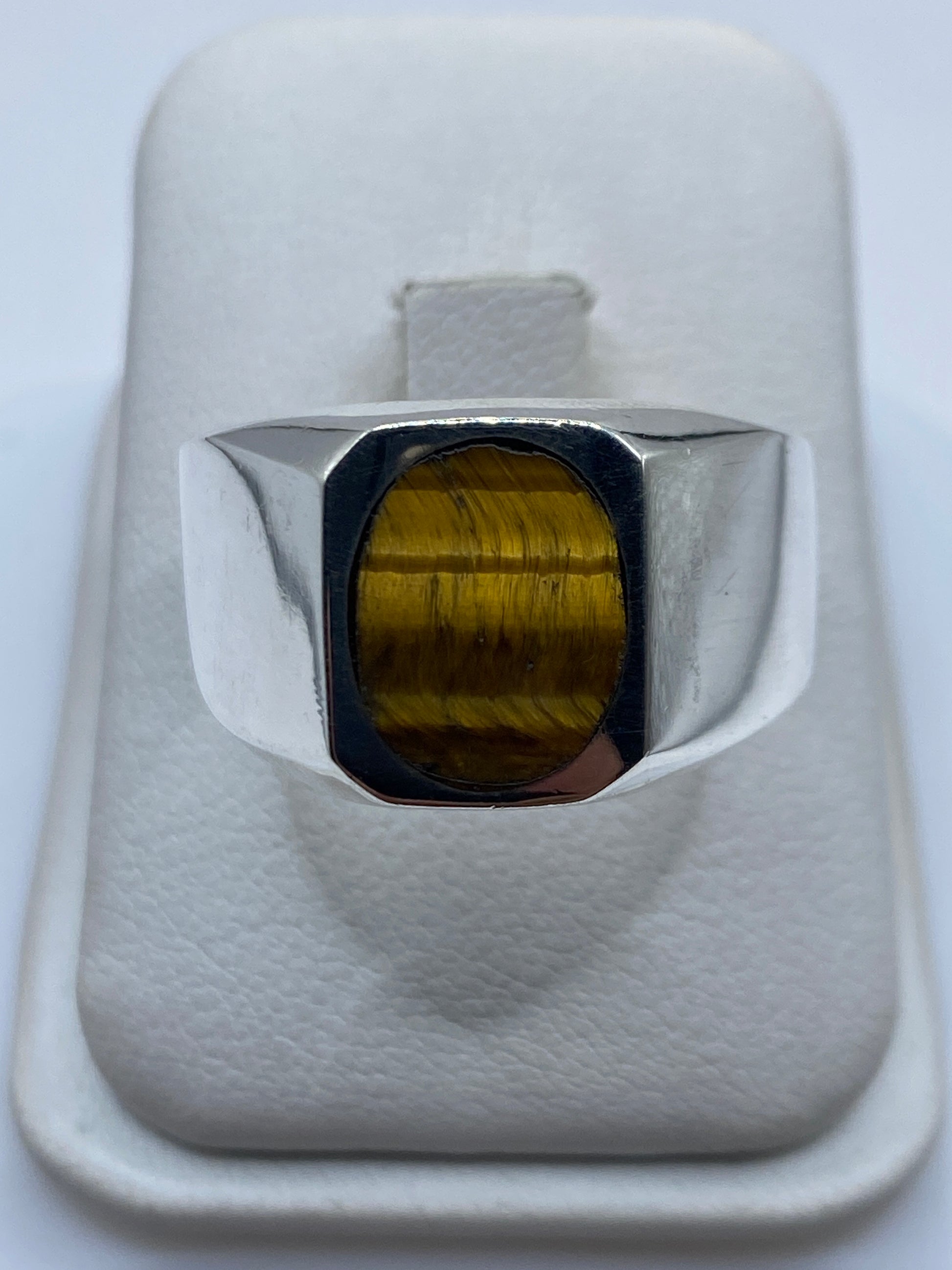 Anillo signet de plata .925 con piedra café, vista de frente en mano de hombre adulto