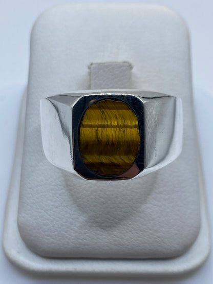 Anillo signet de plata .925 con piedra café, vista de frente en mano de hombre adulto