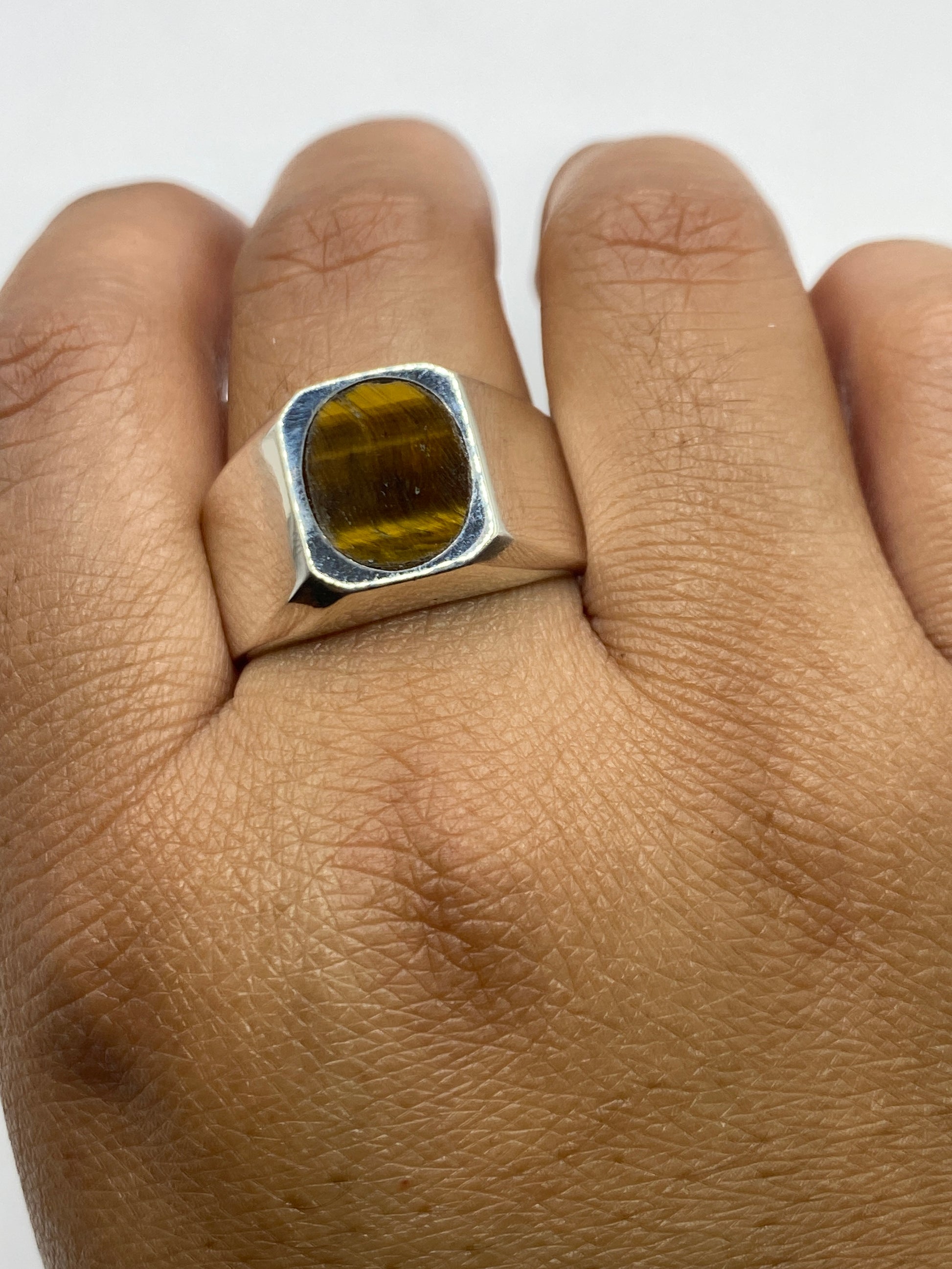 Piedra café natural del anillo signet bajo luz, tonalidad profunda visible