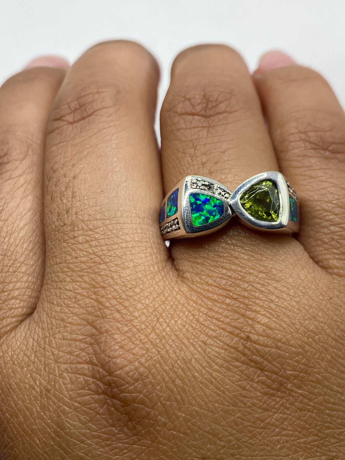 Anillo de plata en mano de mujer, ópalo azul brillante con reflejos verdes, sello .925 visible