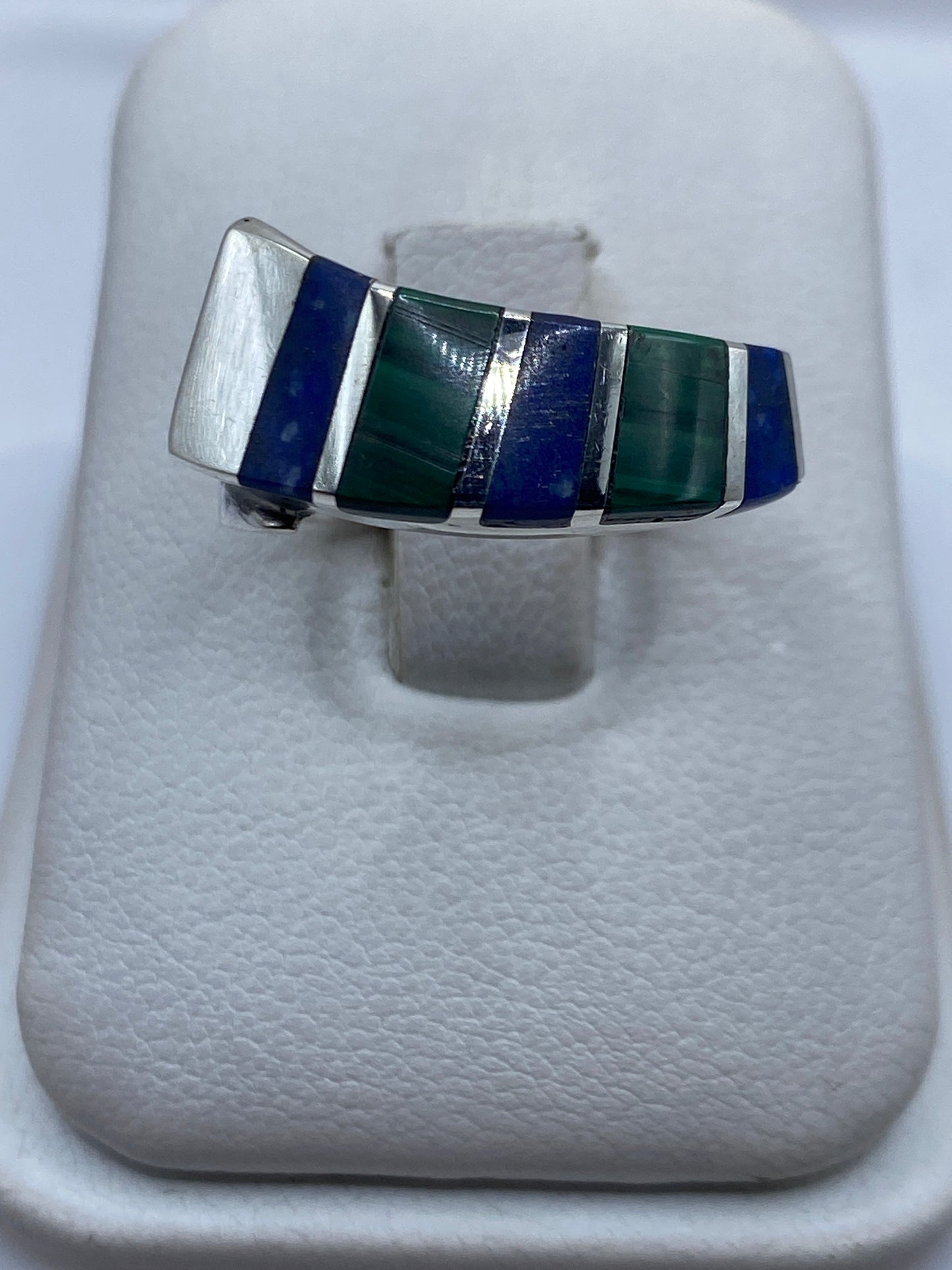 Anillo de plata con malaquita verde en bandas geométricas sobre dedo unisex