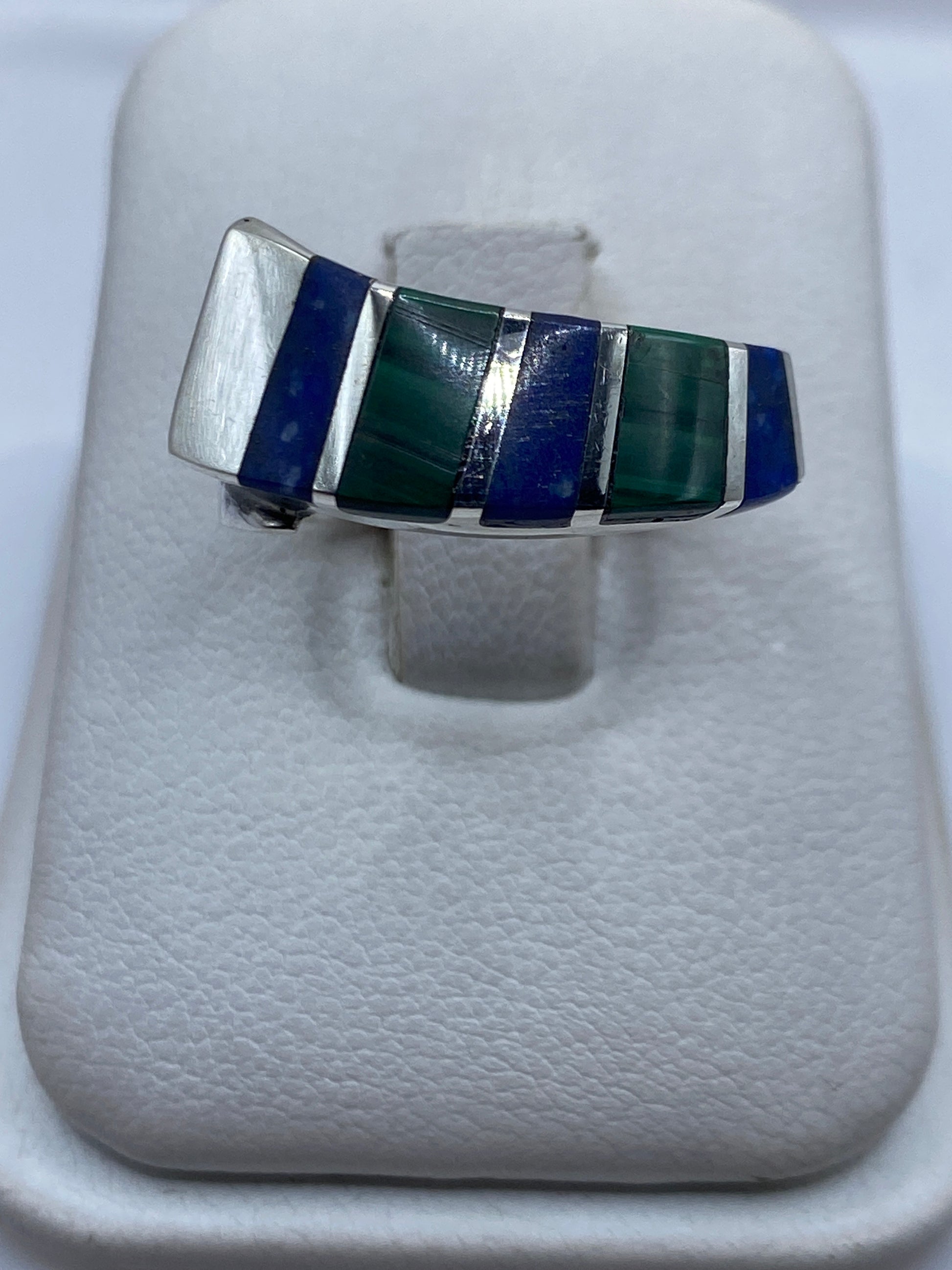 Anillo de plata con malaquita verde en bandas geométricas sobre dedo unisex