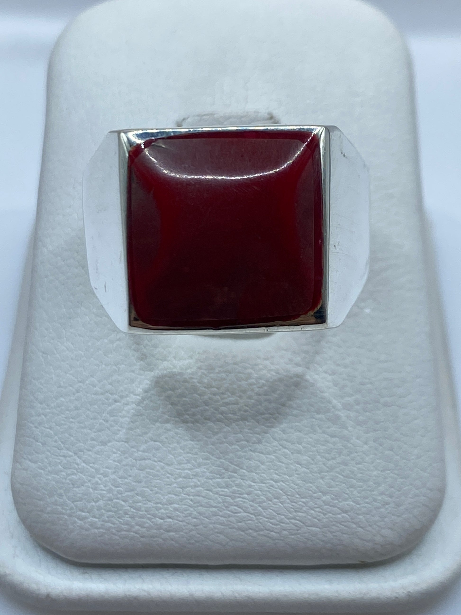 Anillo de plata .925 con sello de coral rojo sobre dedo masculino