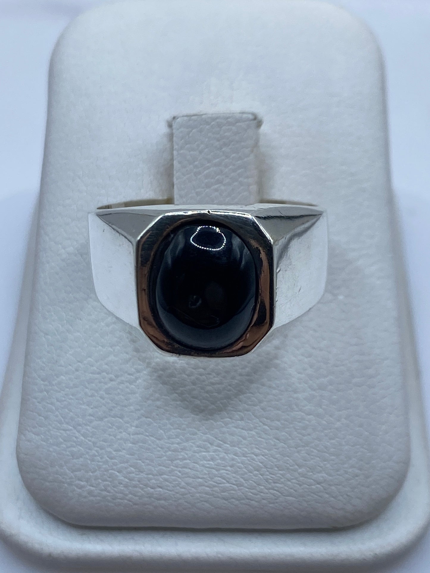 Anillo sello de plata con ónix negro oval en la mano de una persona