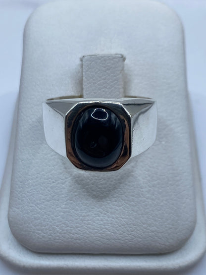 Anillo sello de plata con ónix negro oval en la mano de una persona