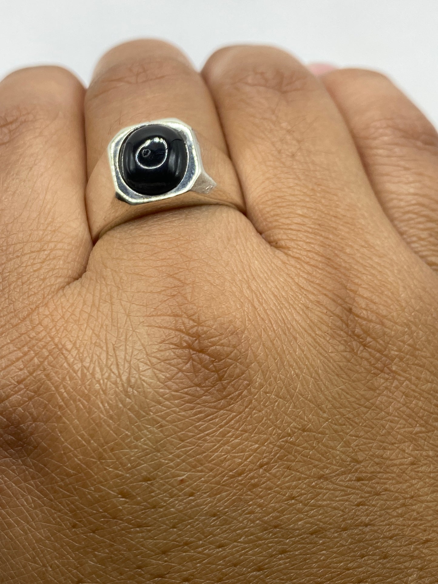 Anillo con sello de ónix sobre fondo gris, mostrando peso y presencia