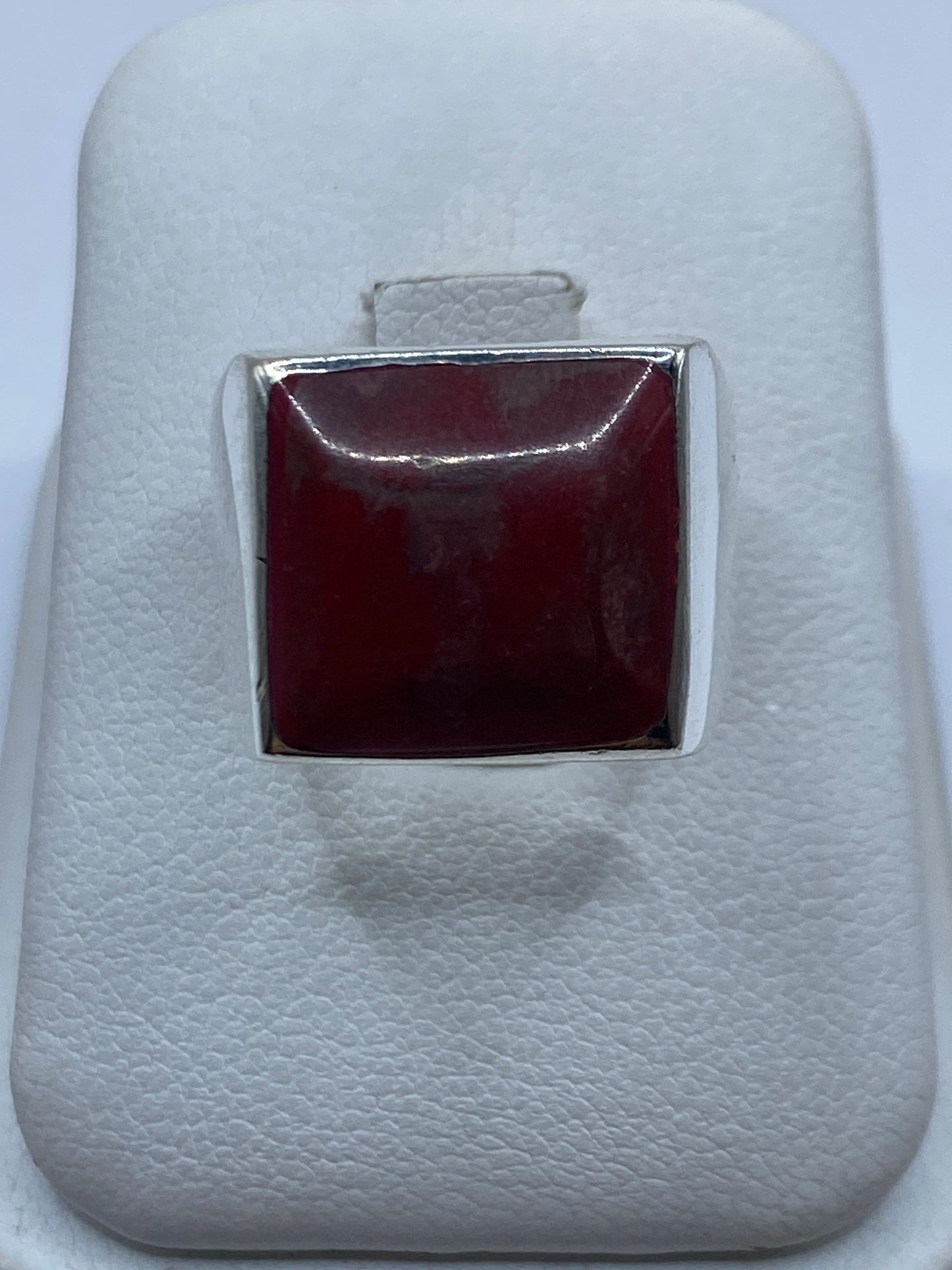 Anillo de plata con coral rojo cuadrado en la mano de una mujer