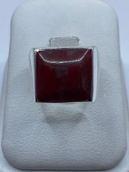 Anillo de plata con coral rojo cuadrado en la mano de una mujer