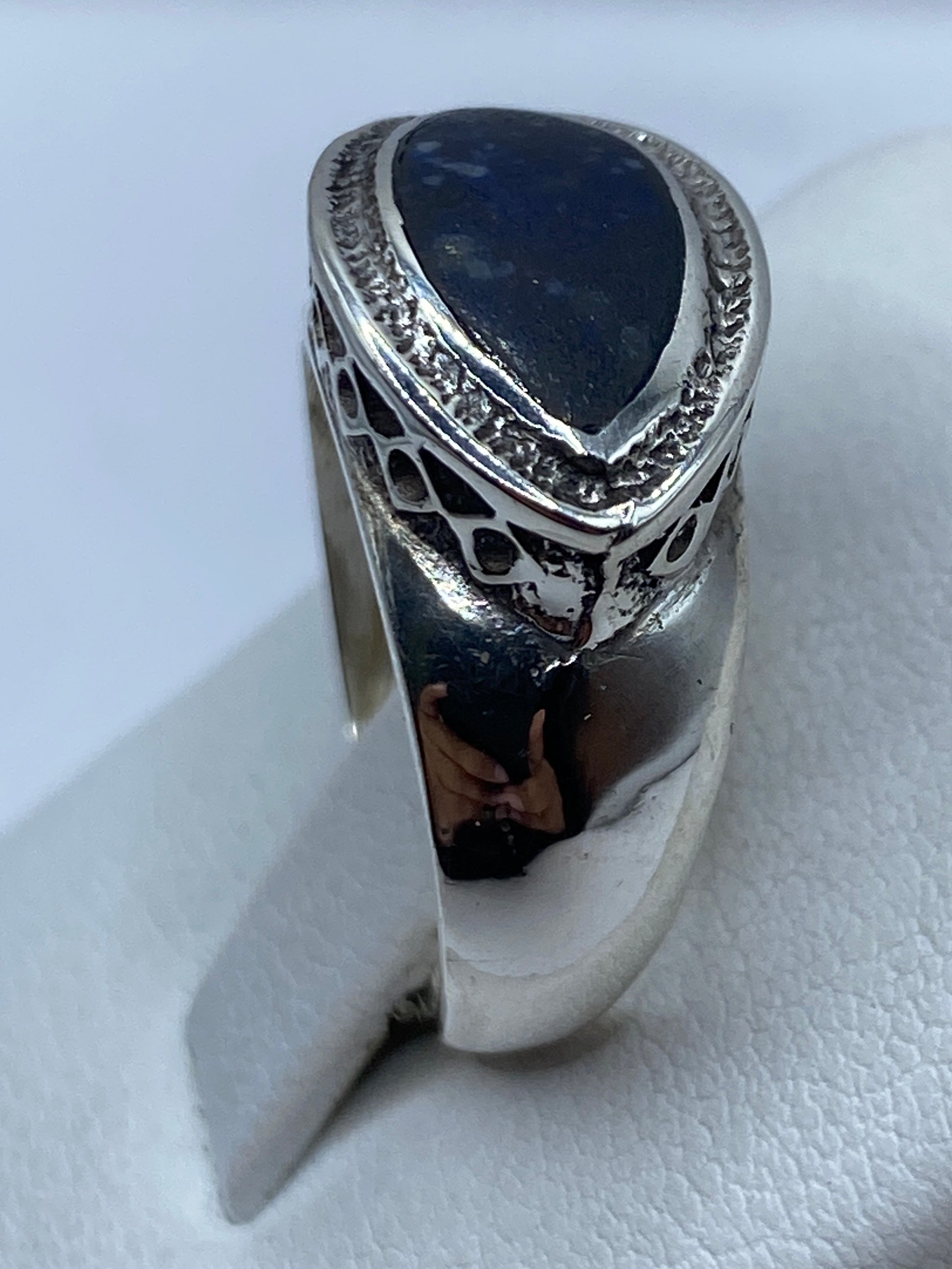 Anillo de lapislázuli en la mano, piedra azul profunda con vetas doradas características