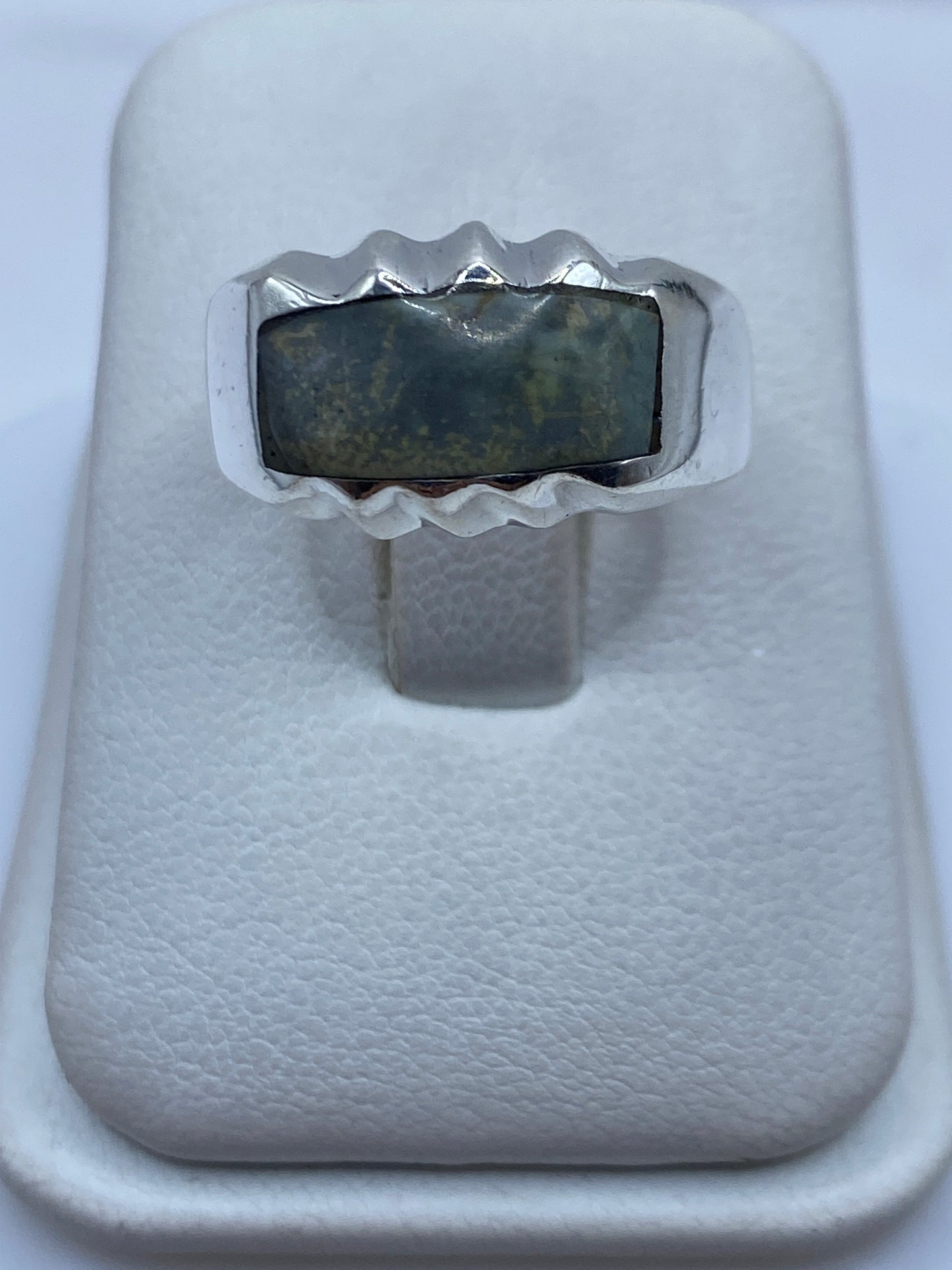 Anillo de plata con piedra engastada, diseño geométrico moderno, vista frontal en estuche blanco