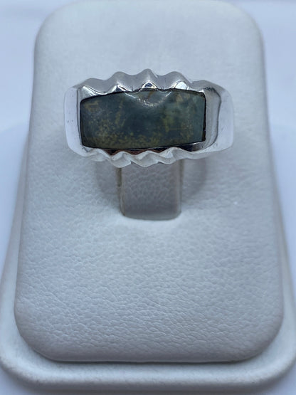 Anillo de plata con piedra engastada, diseño geométrico moderno, vista frontal en estuche blanco
