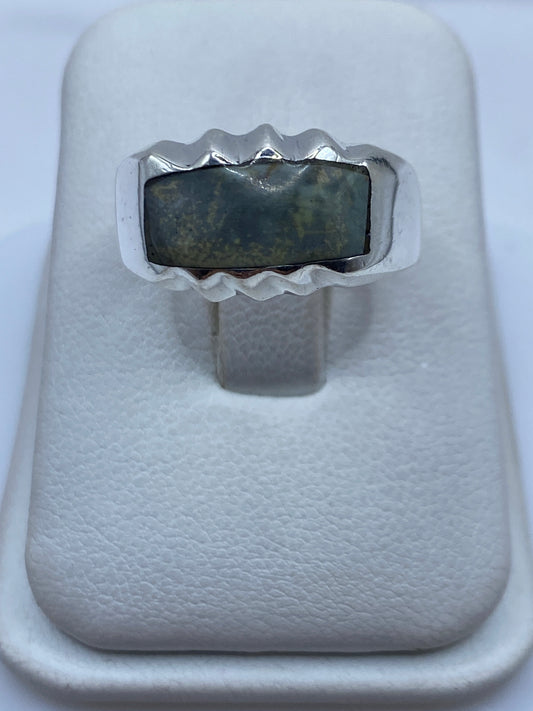 Anillo de plata con piedra engastada, diseño geométrico moderno, vista frontal en estuche blanco