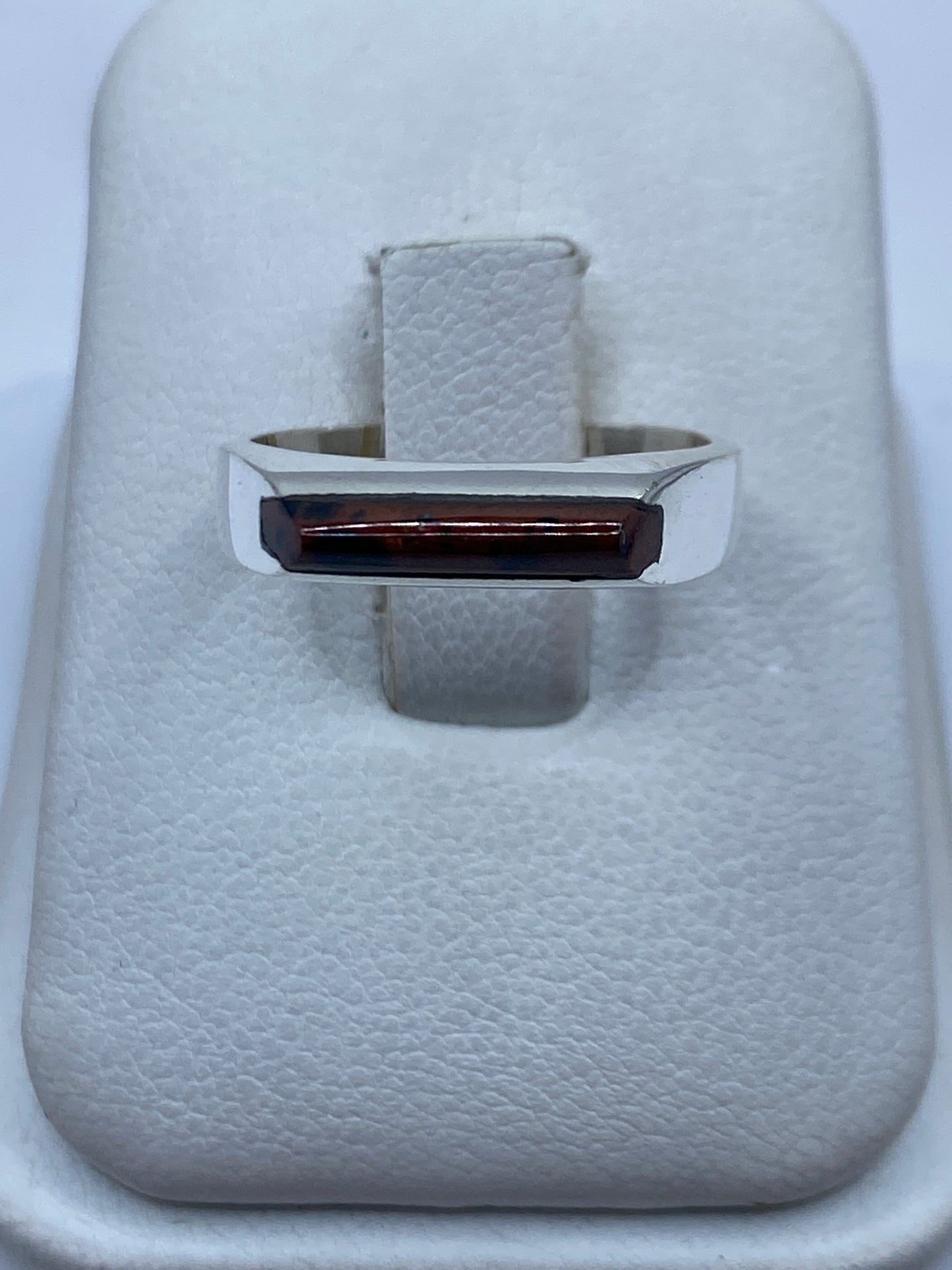 Anillo de plata con piedra engastada en la mano de una mujer, diseño geométrico moderno