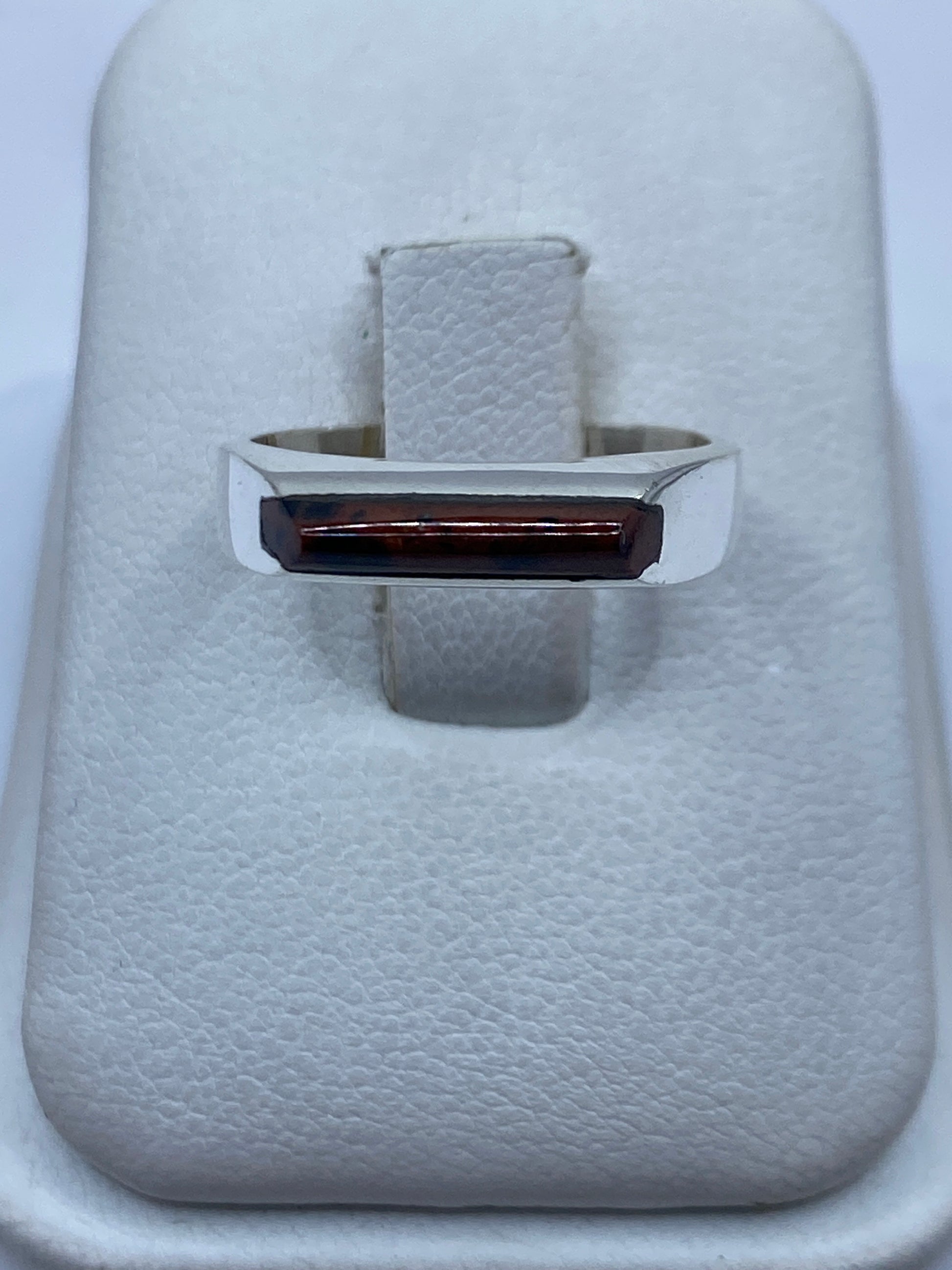 Anillo de plata con piedra engastada en la mano de una mujer, diseño geométrico moderno