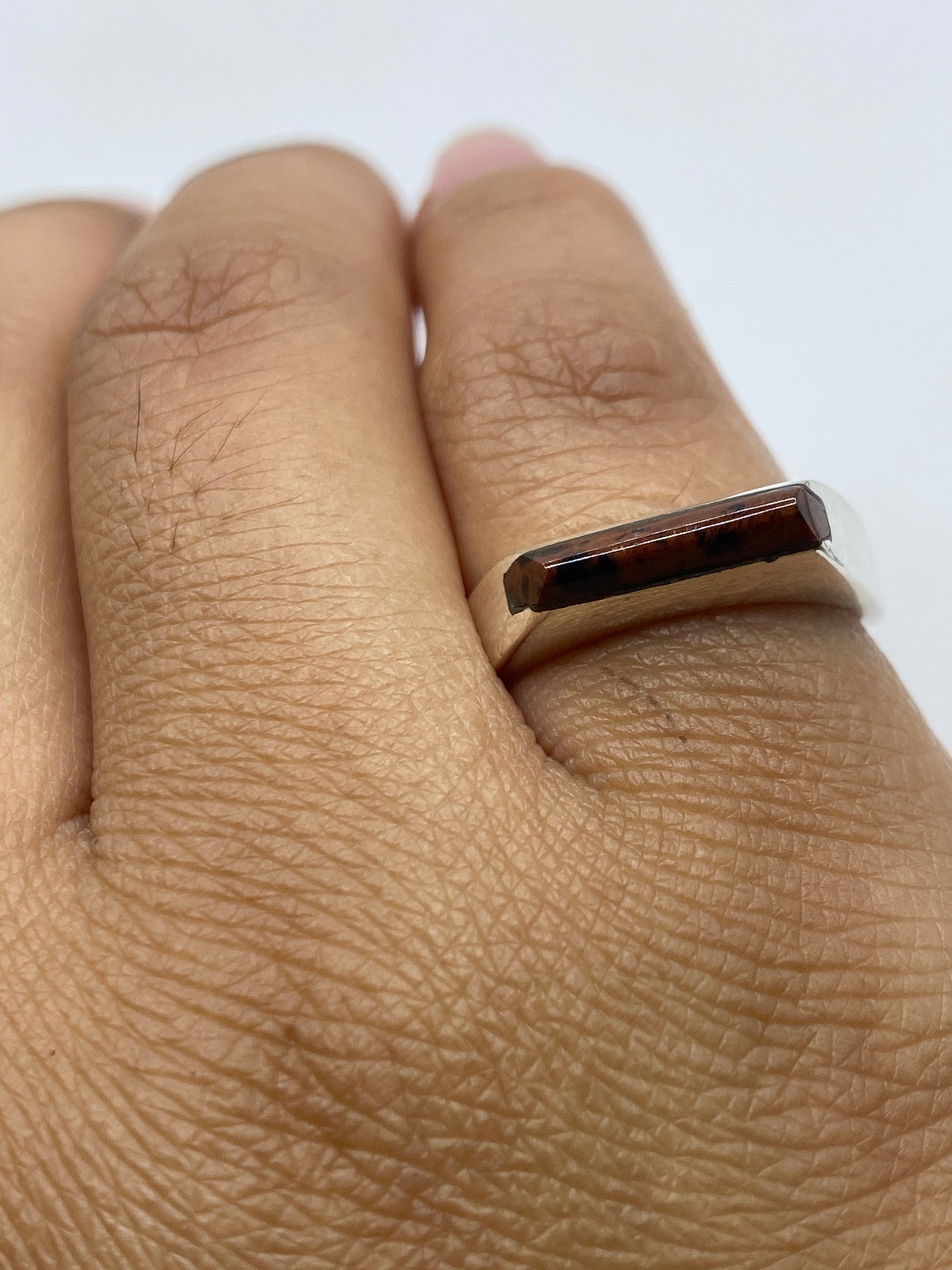 Anillo sobre estuche blanco, piedra engastada brillando bajo luz natural