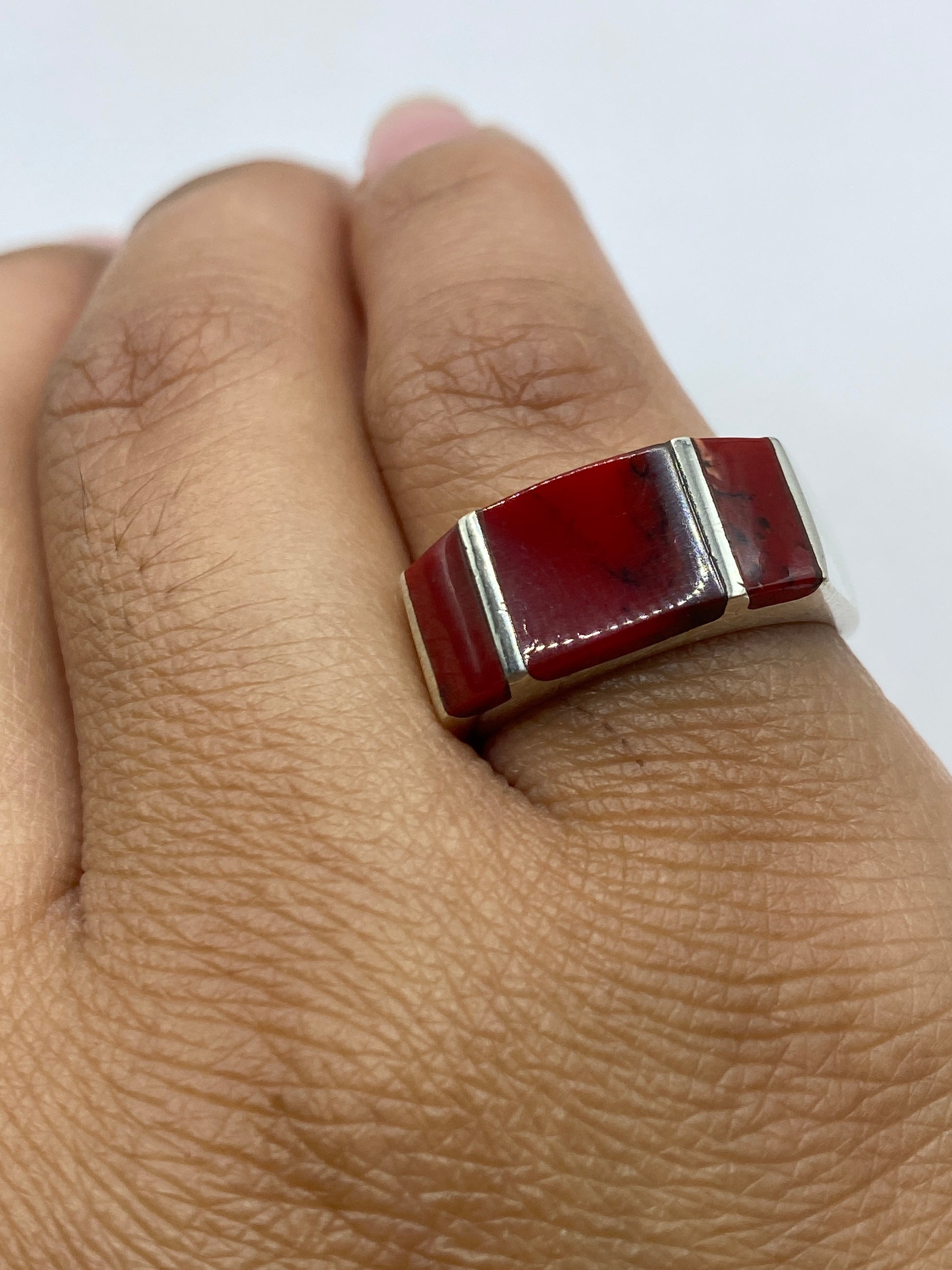 Anillo de coral rojo en la mano mostrando el diseño geométrico y presencia