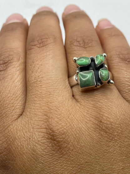 Anillo de malaquita sobre fondo gris, vista superior con luz natural mostrando las vetas verdes de la piedra