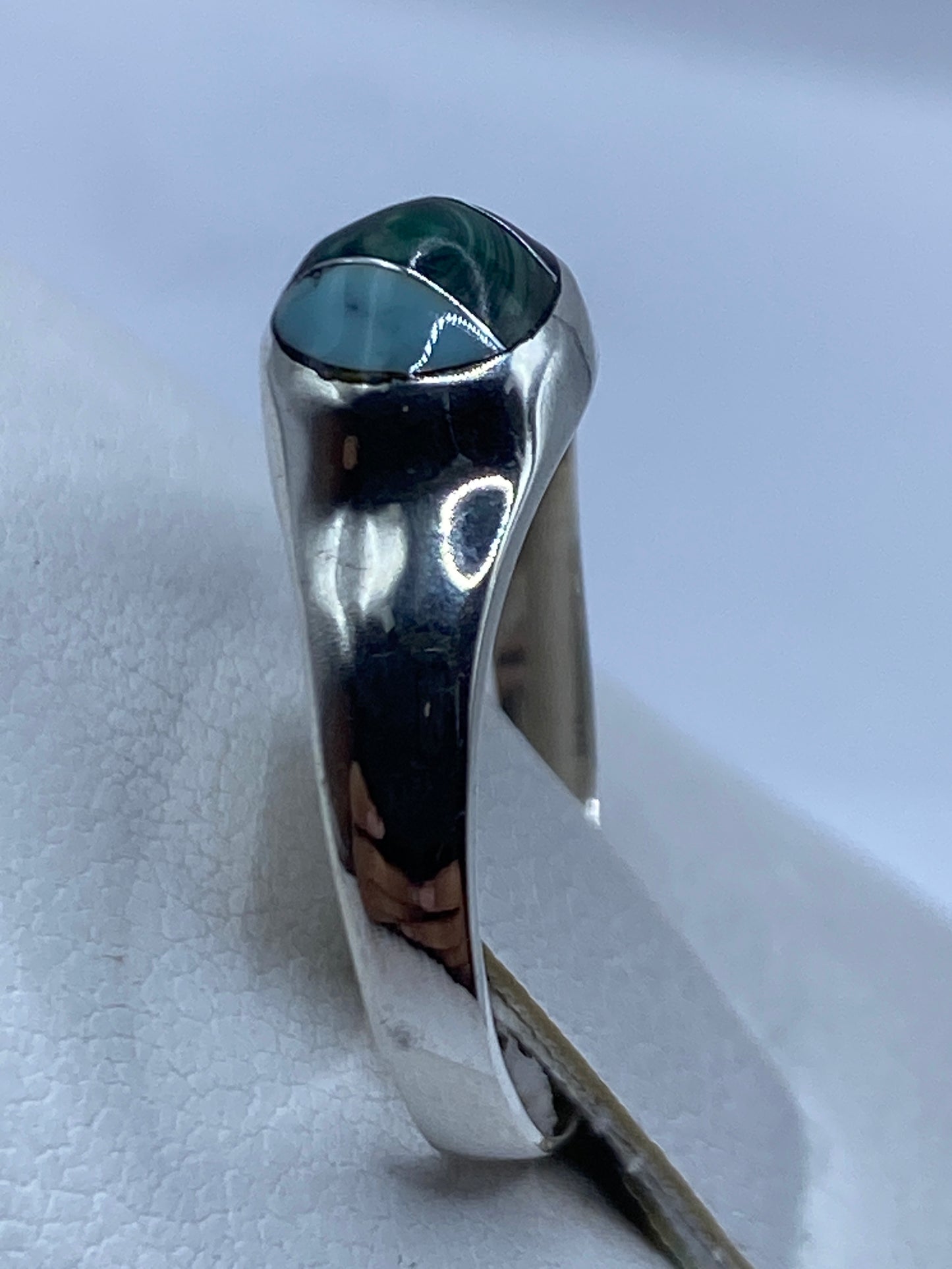 Detalle en mano del anillo de malaquita con vetas verdes naturales