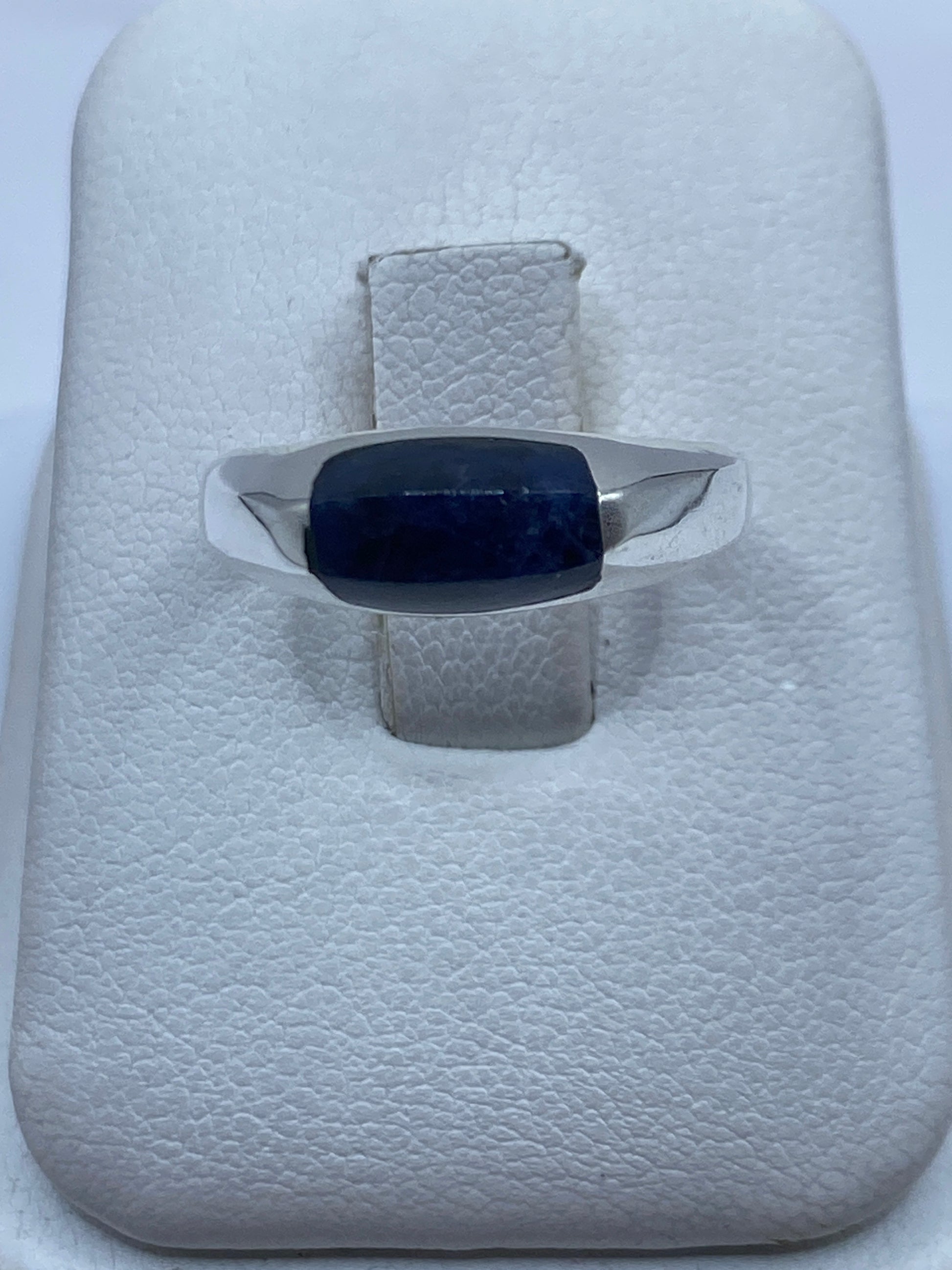 Anillo de plata con lapislázuli azul en la mano de un hombre mostrando el detalle de la piedra natural