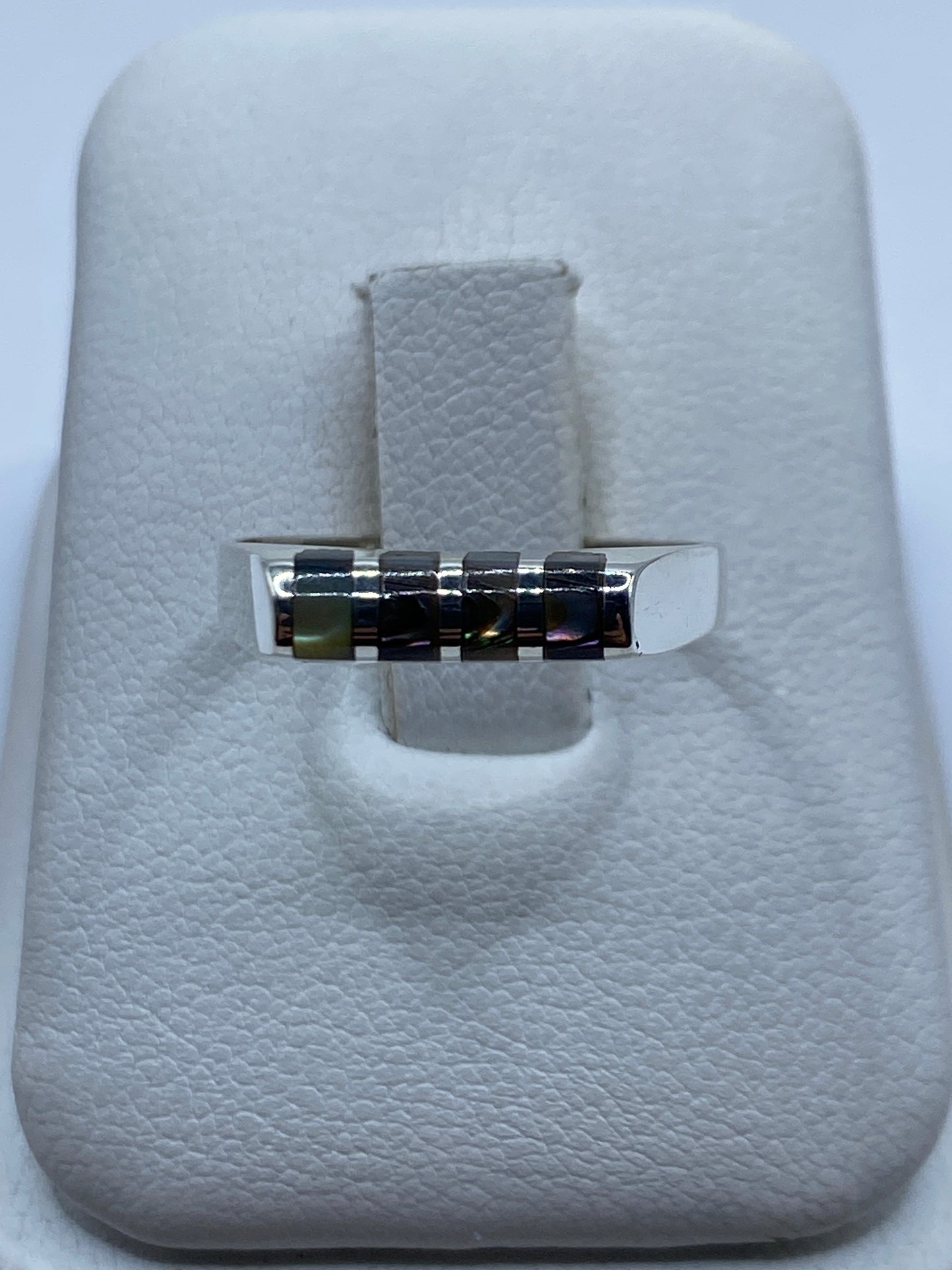 Anillo de plata minimalista con piedras engastadas en la banda, vista frontal sobre estuche blanco