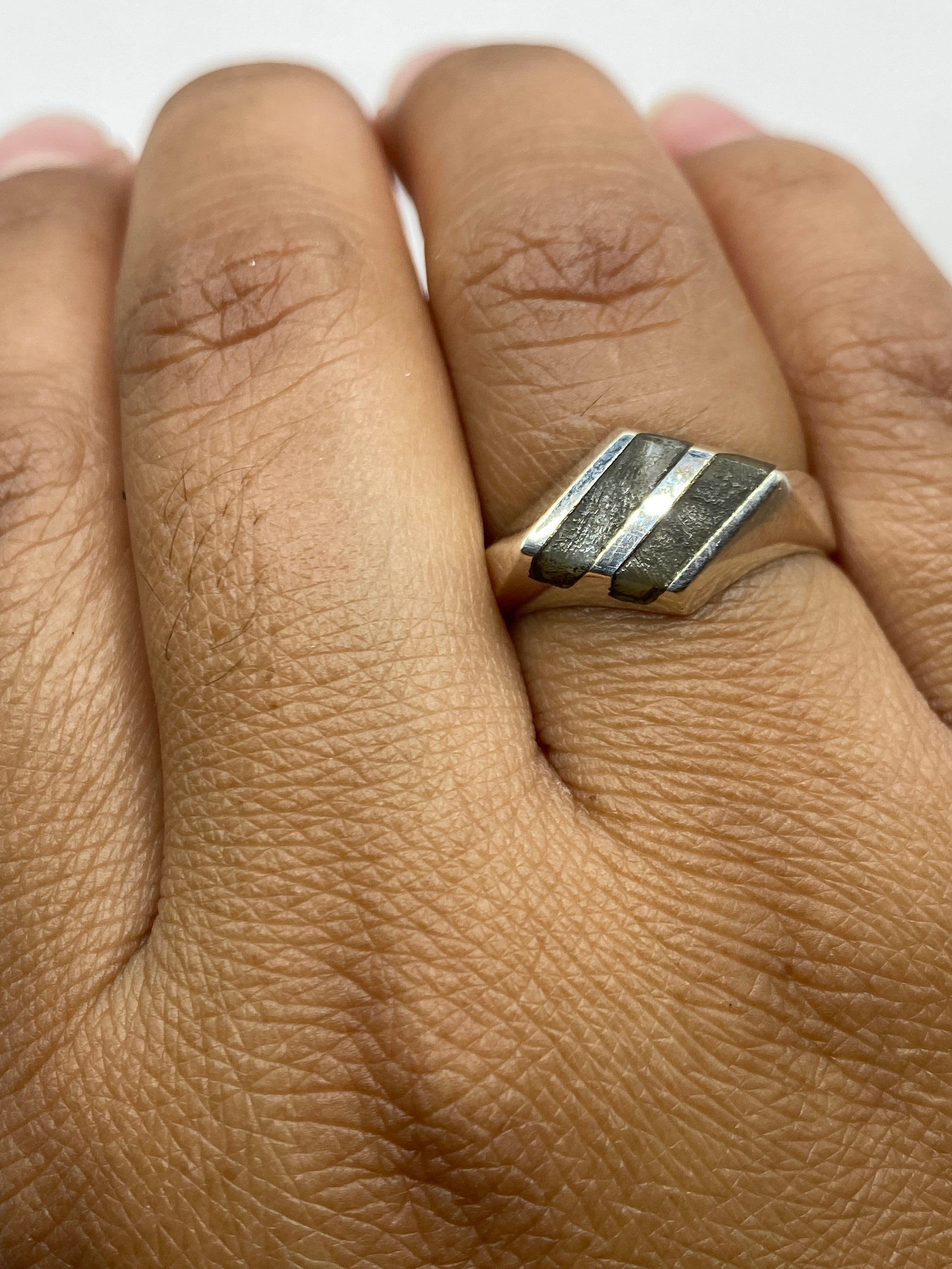 Anillo en la mano demostrando proporción y presencia del diseño geométrico unisex