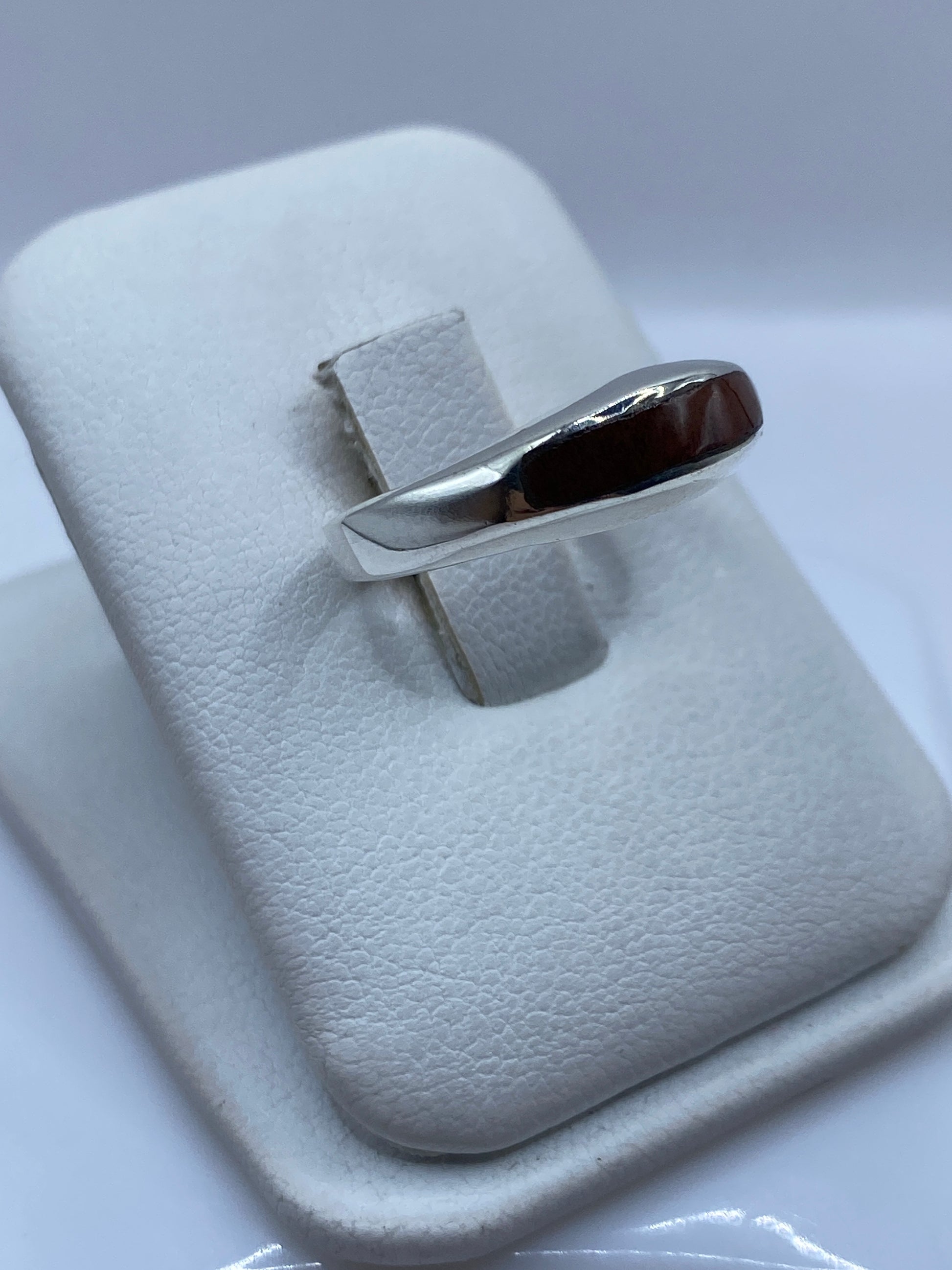 Anillo plata onix café llevado en mano, mostrando el engaste limpio