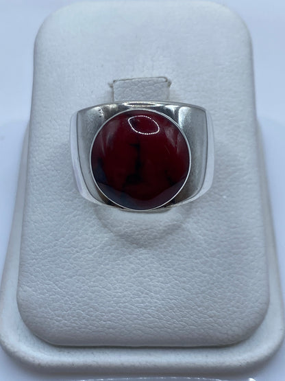 Anillo de plata con coral rojo natural engastado, descansando en estuche blanco