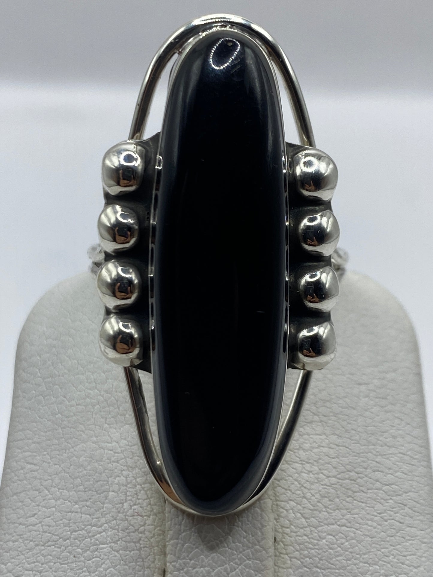 Anillo en la mano de una mujer, ónix negro pulido brillante, diseño escultural