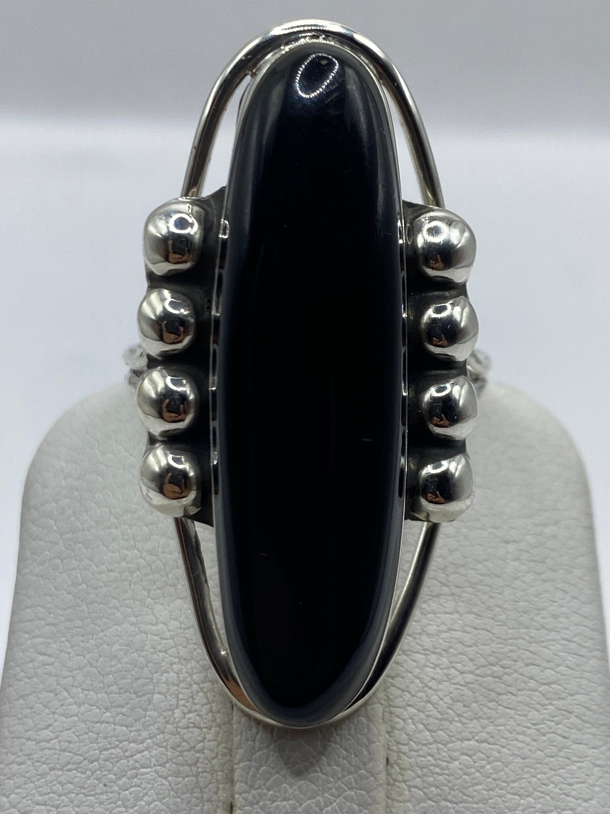 Anillo en la mano de una mujer, ónix negro pulido brillante, diseño escultural