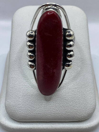 Anillo de plata con coral rojo ovalado, vista frontal sobre soporte blanco