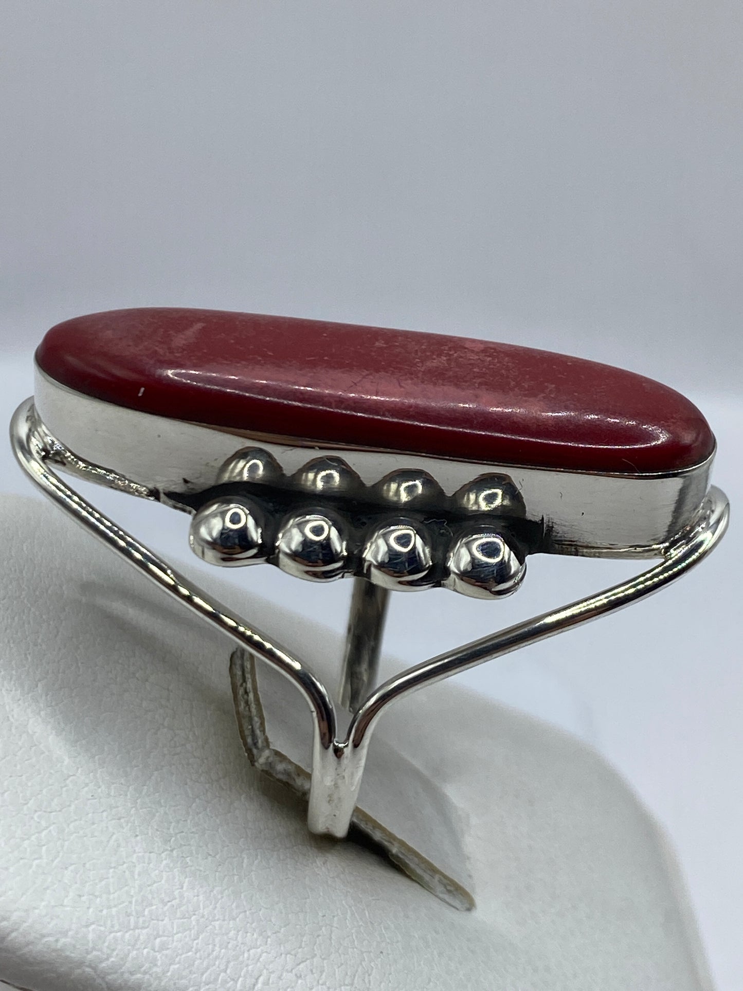 Detalle lateral del anillo de coral rojo mostrando el marco de plata pulida
