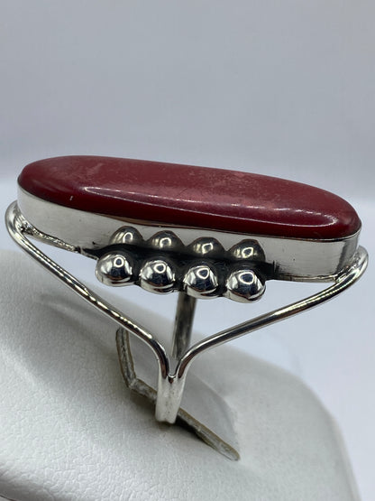 Detalle lateral del anillo de coral rojo mostrando el marco de plata pulida