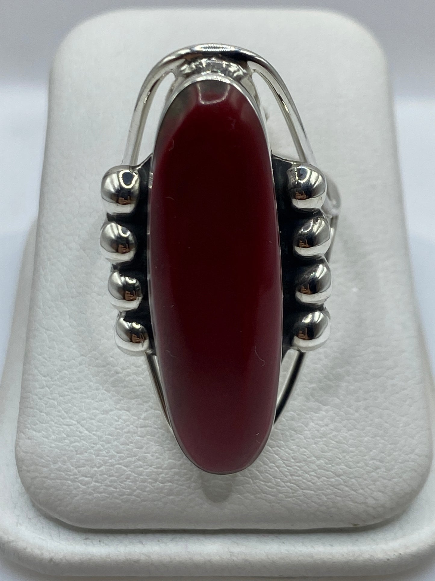 Anillo de plata con coral rojo solitario engastado, sobre fondo blanco