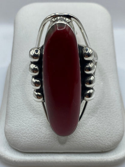 Anillo de plata con coral rojo solitario engastado, sobre fondo blanco
