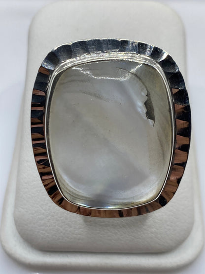 Anillo de plata con perla blanca cremosa en la mano de una mujer