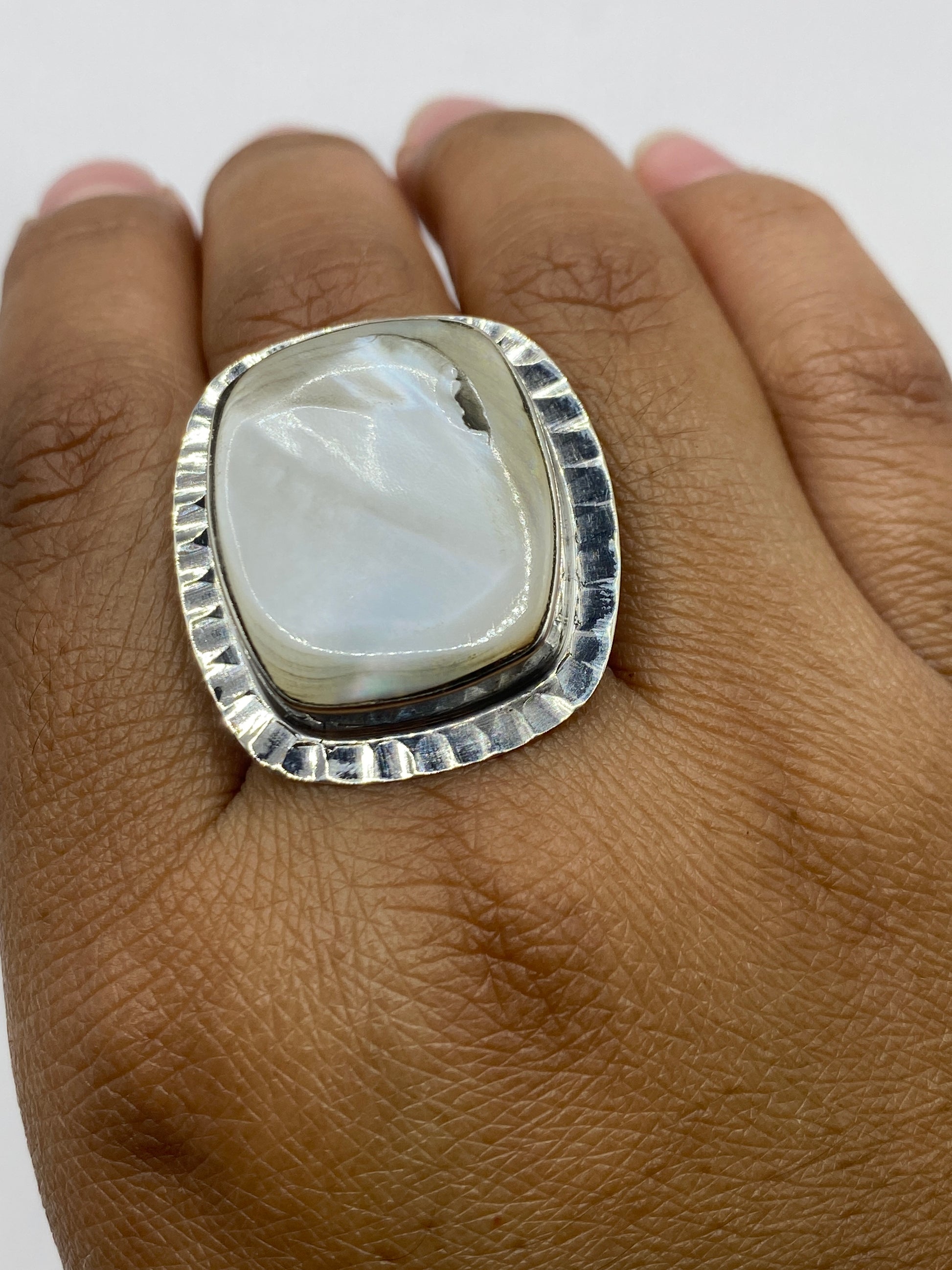 Anillo perla sobre fondo gris mostrando el acabado pulido espejo y el sello .925
