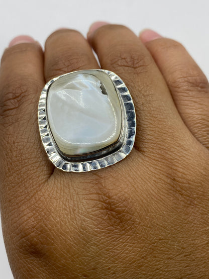 Anillo perla sobre fondo gris mostrando el acabado pulido espejo y el sello .925